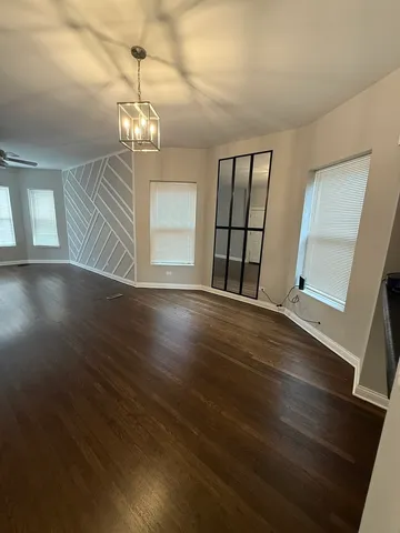 a view of an empty room with wooden floor and windows