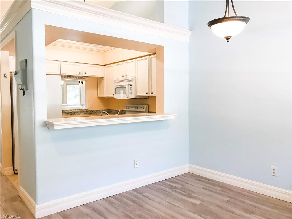 157 Wading Bird Circle, Unit K205 Naples, FL 34110 - Photo 2 of 22 a view of a hallway with wooden floor and a cabinet