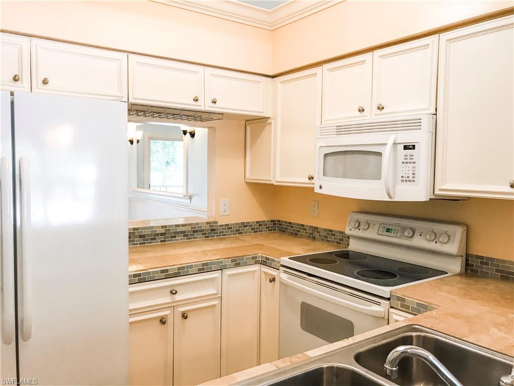 157 Wading Bird Circle, Unit K205 Naples, FL 34110 - Photo 3 of 22 a view of a kitchen with a sink and cabinets