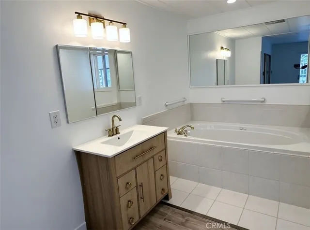 a bathroom with a bathtub a mirror a sink and vanity