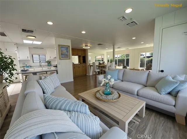 a living room with furniture kitchen view and a wooden floor