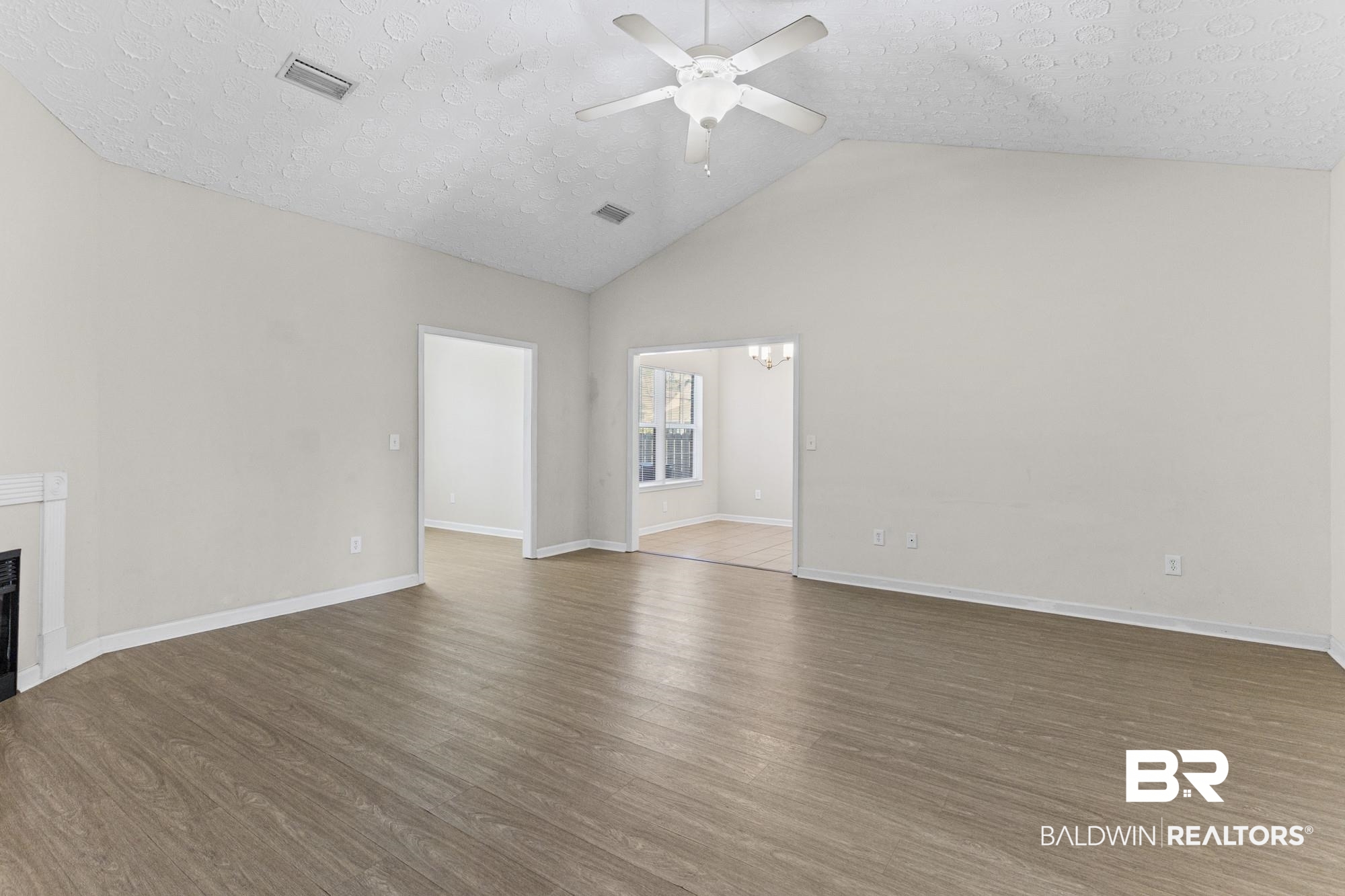 1153 Sloane Cove Foley, AL 36535 - Photo 14 of 25 Unfurnished living room with a fireplace, a high textured ceiling, dark wood-style flooring, and ceiling fan