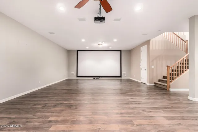 a view of an empty room with wooden floor and stairs