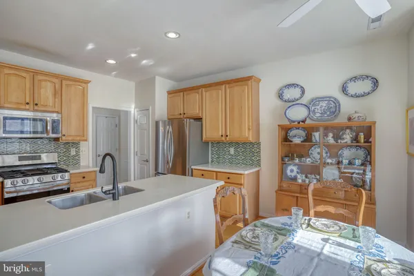a kitchen with stainless steel appliances granite countertop a refrigerator a stove and a sink with wooden cabinets