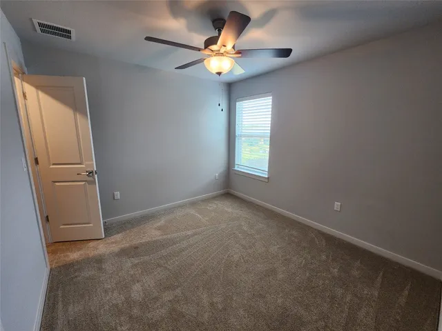an empty room with closet and a chandelier fan