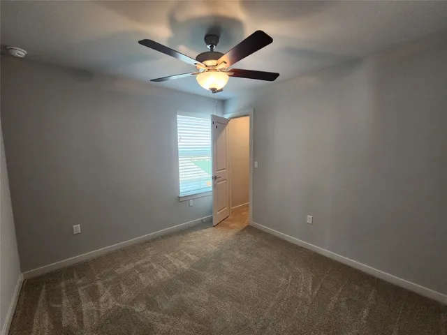 an empty room with closet and a ceiling fan