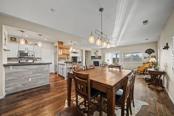 a view of a dining room and livingroom with furniture wooden floor a rug a chandelier