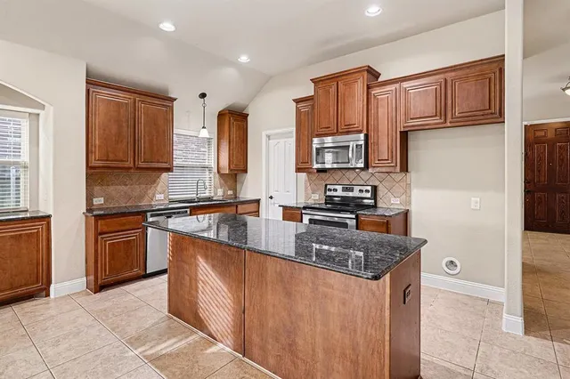 a kitchen with stainless steel appliances granite countertop a stove a sink dishwasher a refrigerator and cabinets with wooden floor