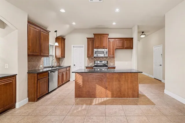 a large kitchen with a large counter top stainless steel appliances and cabinets