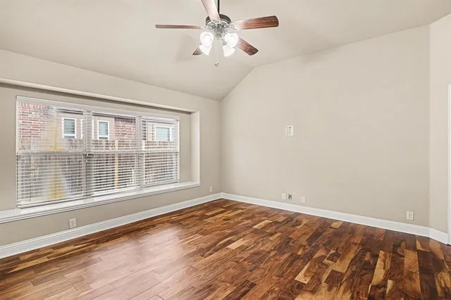 a view of an empty room with a window and wooden floor