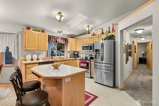 a kitchen with stainless steel appliances granite countertop a sink refrigerator and cabinets