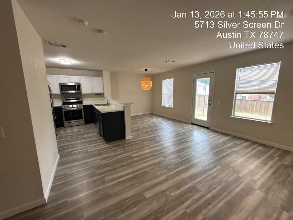 5713 Silver Screen Drive Austin, TX 78747 - Photo 21 of 21 Kitchen with white cabinetry, light countertops, stainless steel appliances, dark cabinets, and open floor plan
