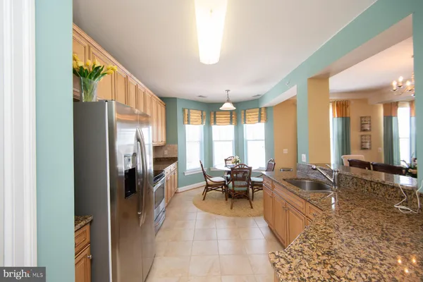 a kitchen with stainless steel appliances granite countertop a stove top oven a sink dishwasher and a refrigerator with wooden floor