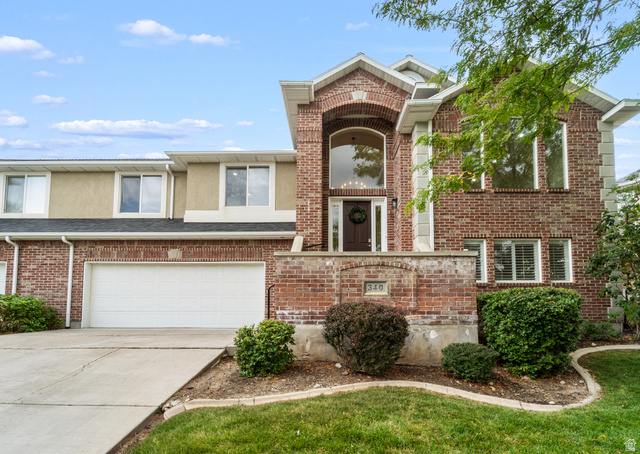 Brick exterior with a prominent arched entry, two-car garage, and established landscaping