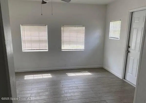 an empty room with wooden floor and windows
