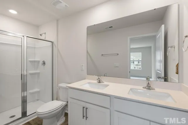 a bathroom with a sink toilet double vanity and shower