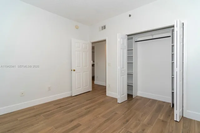 an empty room with wooden floor & closet area