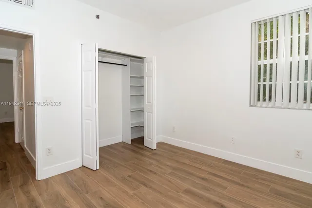 an empty room with wooden floor & closet and windows