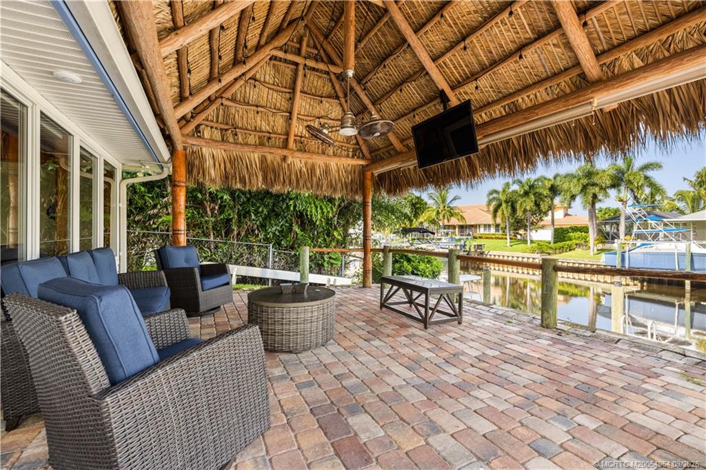 1359 Southwest Dyer Point Road Palm City, FL 34990 - Photo 32 of 55 a view of a patio with a dining table and chairs with wooden floor