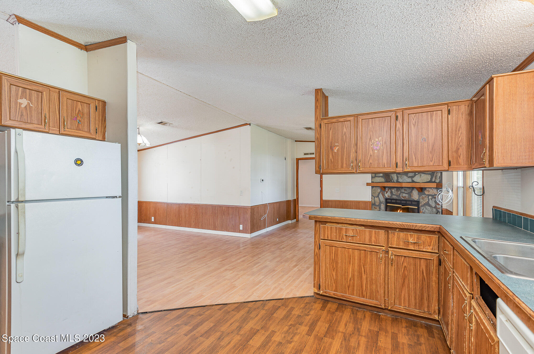 823 Phyllis Way Cocoa, FL 32926 - Photo 9 of 28 a kitchen with granite countertop a refrigerator a stove a sink and white cabinets with wooden floor