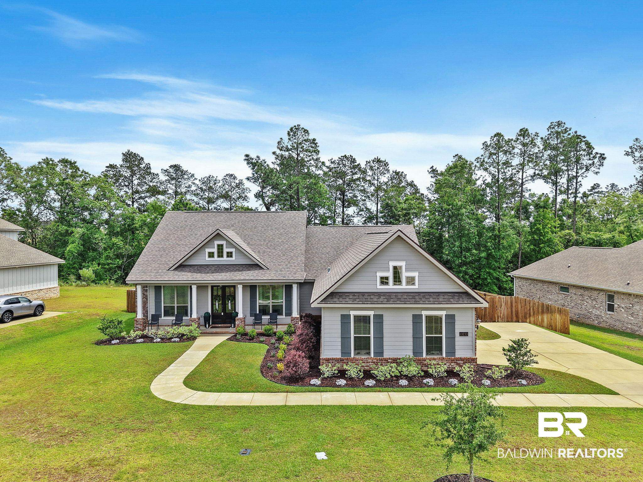 13233 Ibis Boulevard Daphne, AL 36527 - Photo 1 of 100 Single-story residence featuring light gray siding, dark gray shutters, and a prominent front porch with white columns