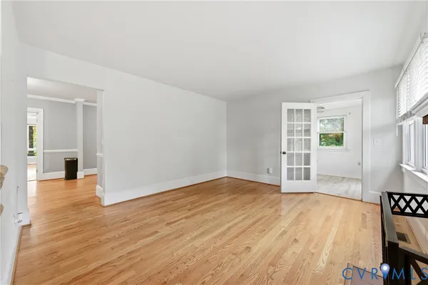 an empty room with wooden floor and windows