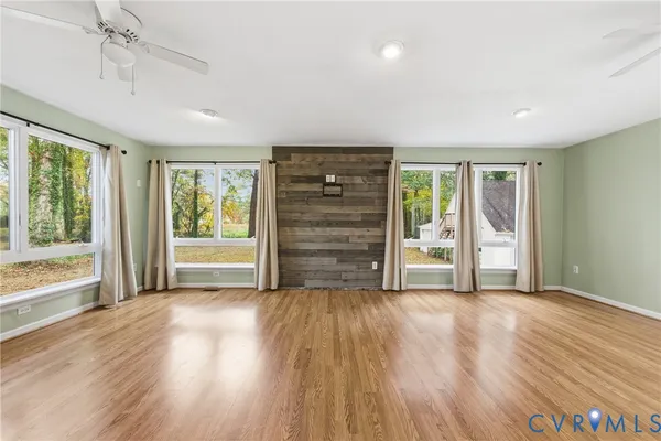 an empty room with wooden floor closet and windows