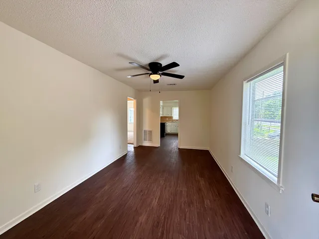 a view of an empty room with wooden floor and a window