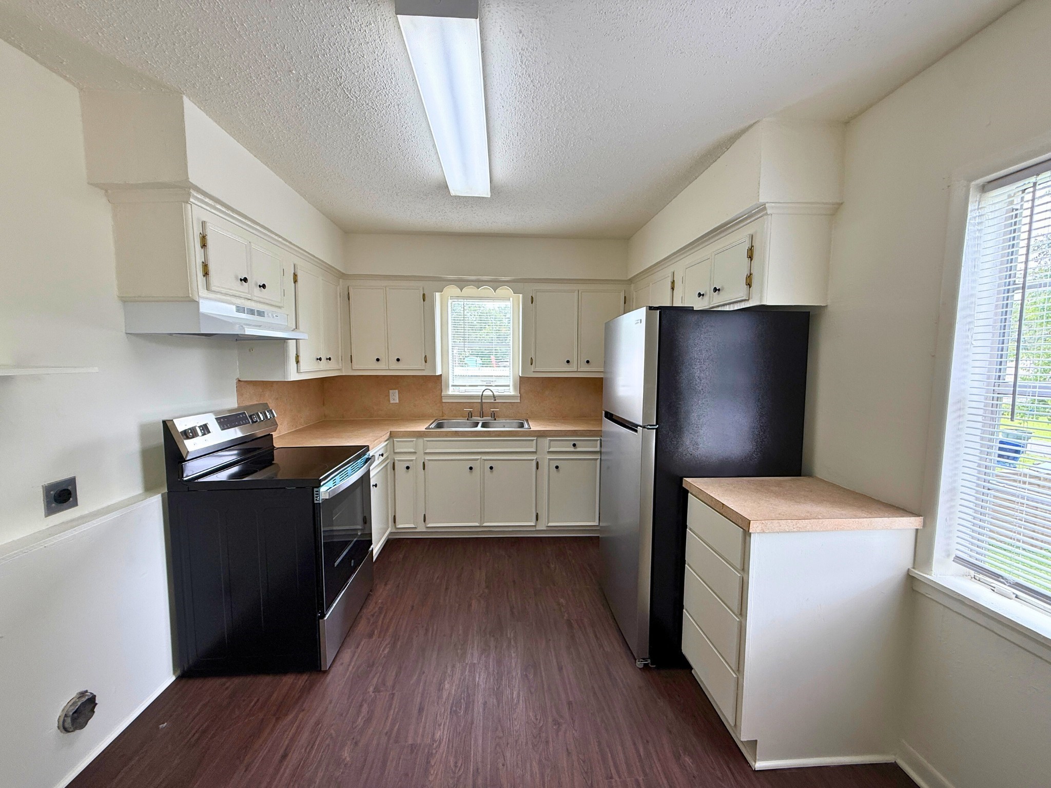 214 Crawford Street Huntsville, TX 77340 - Photo 14 of 24 a kitchen with a refrigerator a sink dishwasher and a stove with wooden floor