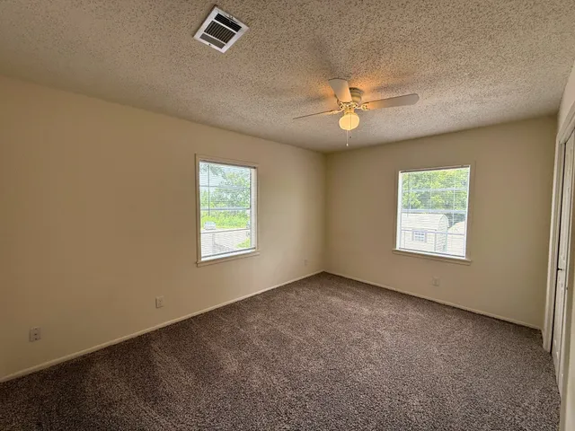 an empty room with windows and ceiling fan