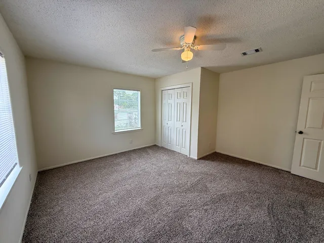 an empty room with windows and fan