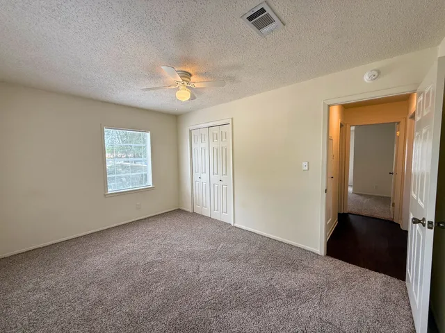 an empty room with windows and fan