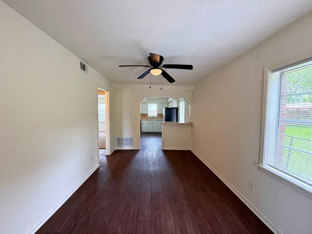a view of empty room with wooden floor and fan