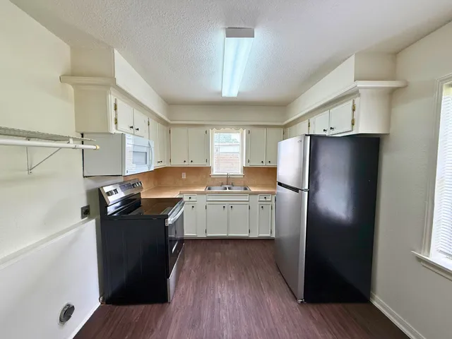 a kitchen with stainless steel appliances a refrigerator a sink dishwasher a stove and white countertops with wooden floor