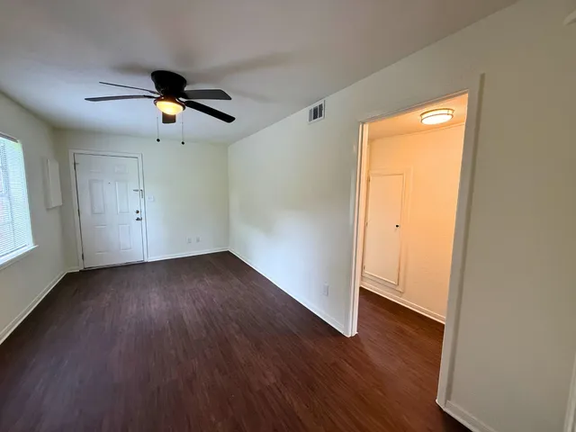 an empty room with wooden floor and windows