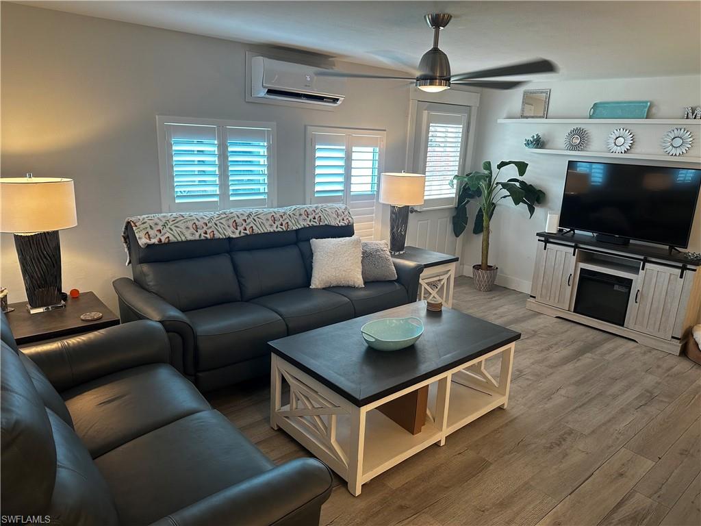 170 Pine Key Lane, Unit 13 Naples, FL 34114 - Photo 18 of 34 Living room featuring wood finished floors, ceiling fan, and a wall mounted mini split