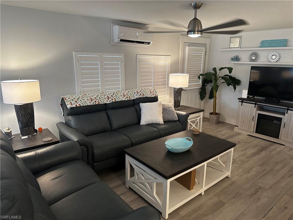 170 Pine Key Lane, Unit 13 Naples, FL 34114 - Photo 20 of 34 Living room featuring a ceiling fan, a wall mounted mini split, and wood finished floors