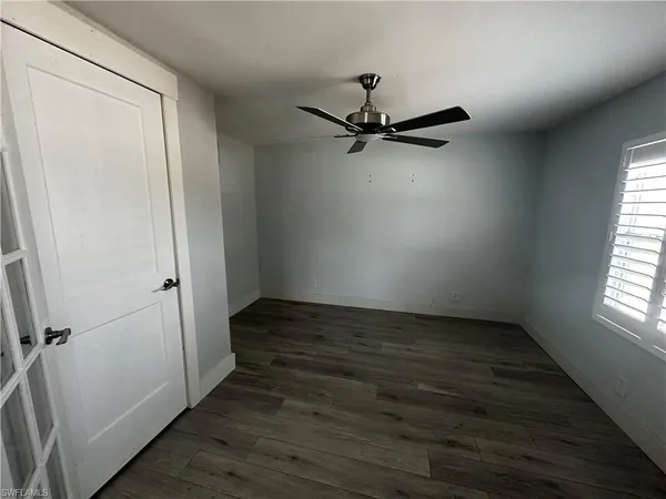 an empty room with wooden floor fan and windows