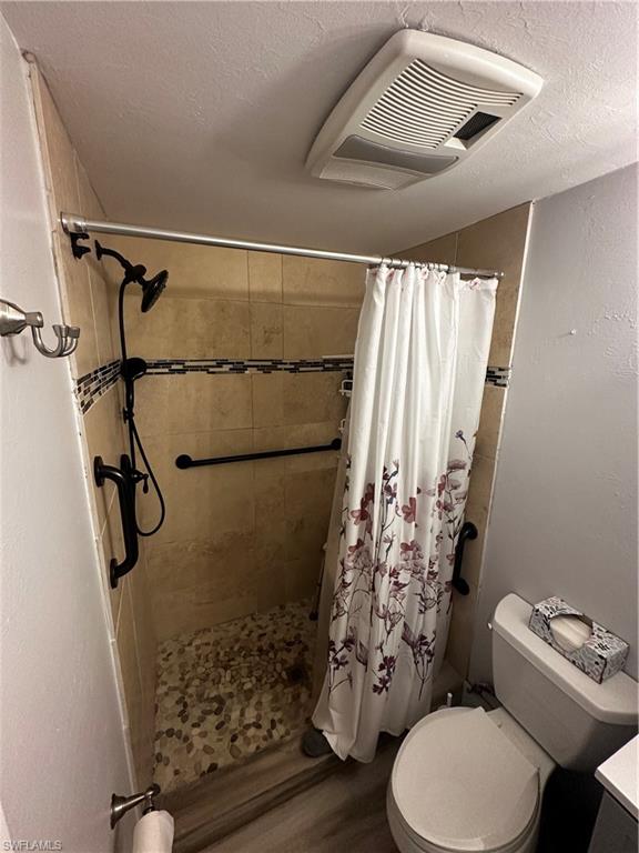 170 Pine Key Lane, Unit 13 Naples, FL 34114 - Photo 5 of 34 Bathroom with a textured ceiling, a stall shower, vanity, a textured wall, and wood finished floors