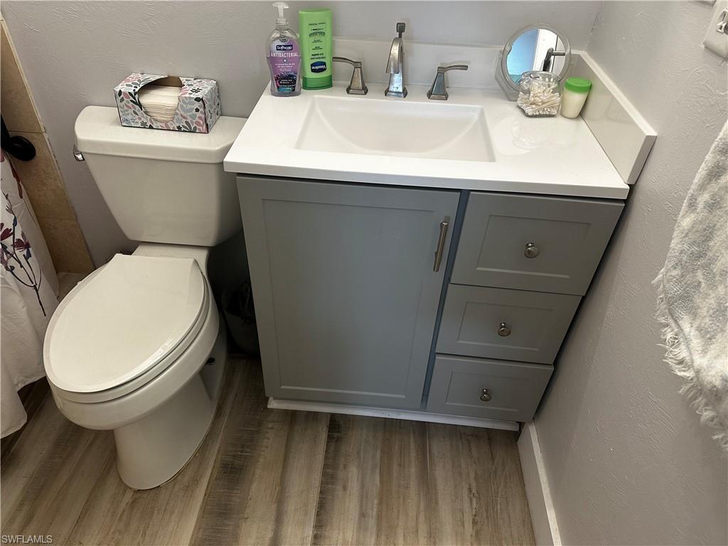 170 Pine Key Lane, Unit 13 Naples, FL 34114 - Photo 6 of 34 Bathroom with a textured wall, vanity, curtained shower, and light wood finished floors