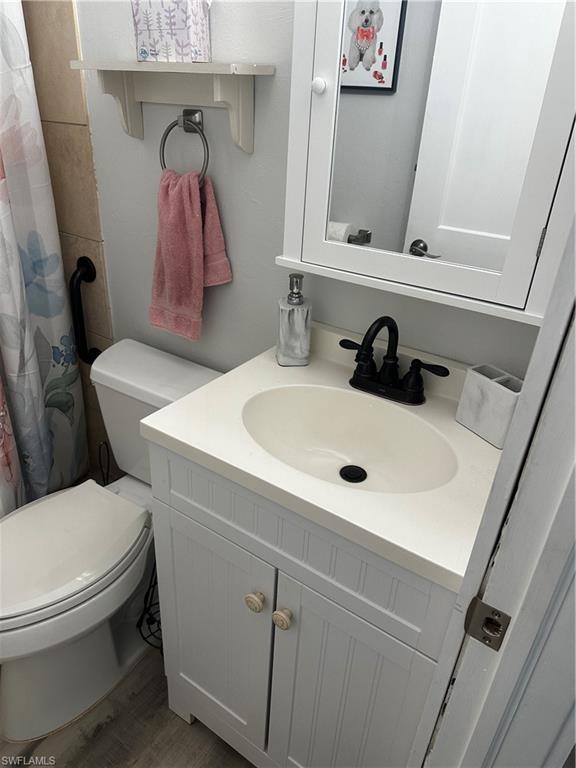 170 Pine Key Lane, Unit 13 Naples, FL 34114 - Photo 7 of 34 Bathroom featuring curtained shower, vanity, and wood finished floors