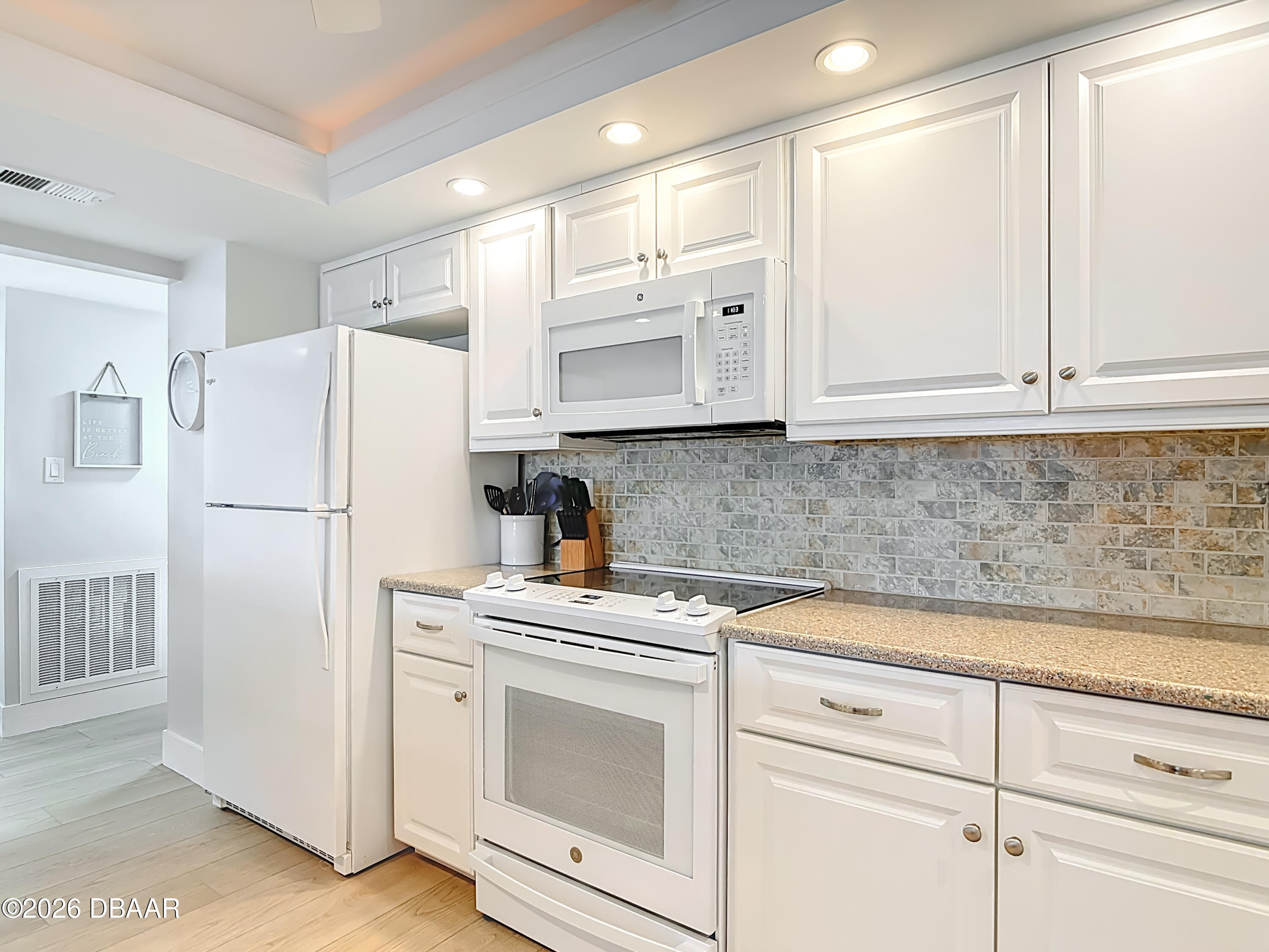 4445 South Atlantic Avenue, Unit 301 Ponce Inlet, FL 32127 - Photo 9 of 45 a kitchen with white cabinets and white appliances