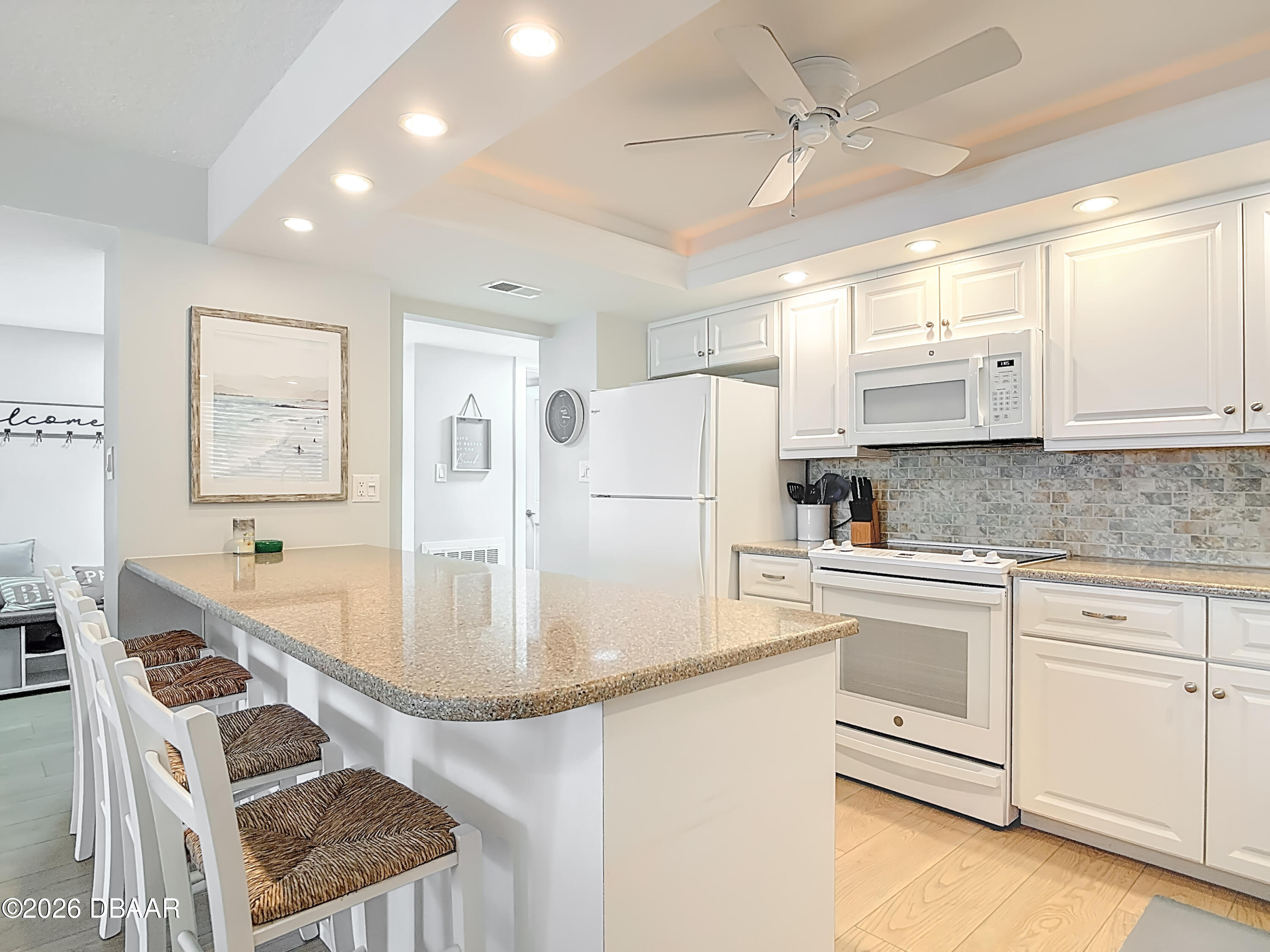 4445 South Atlantic Avenue, Unit 301 Ponce Inlet, FL 32127 - Photo 10 of 45 a kitchen with stainless steel appliances granite countertop a refrigerator a sink dishwasher a stove top oven a dining table and chairs with wooden floor