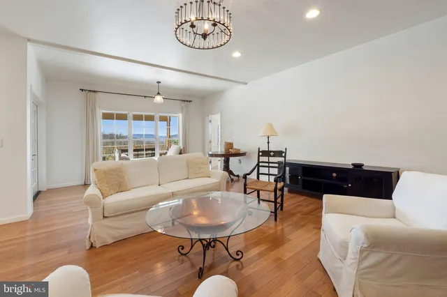a view of a hallway to a livingroom with wooden floor and staircase