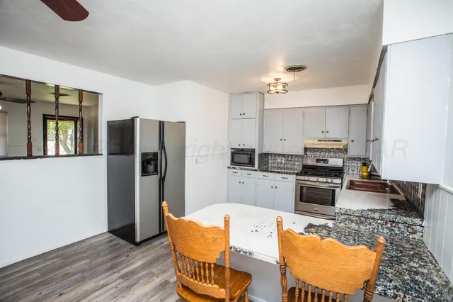 a kitchen with granite countertop a refrigerator stove top oven and sink