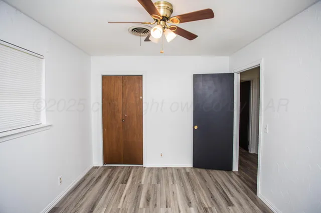 an empty room with closet and a ceiling fan