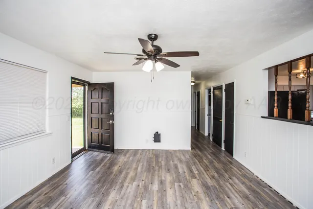 a view of empty room with wooden floor and ceiling fan