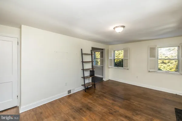 a view of an empty room with window and wooden floor