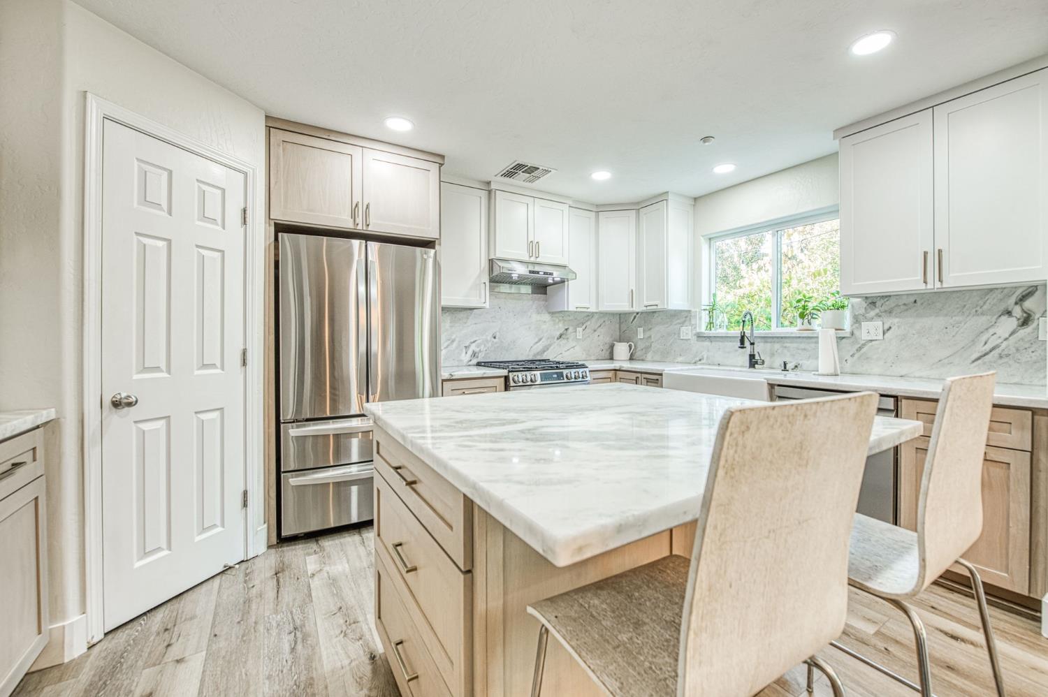5855 East Platt Avenue Fresno, CA 93727 - Photo 31 of 57 a kitchen with stainless steel appliances granite countertop a refrigerator a sink dishwasher and white cabinets with wooden floor