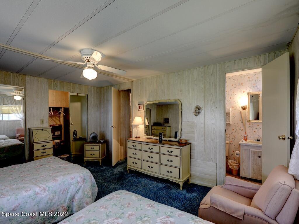 939 Laurel Circle Barefoot Bay, FL 32976 - Photo 23 of 36 a spacious bedroom with a bed and a chandelier